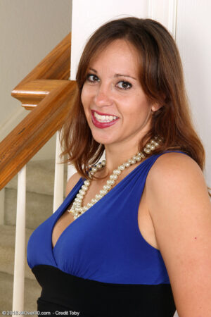 Elegant brunette MILF Cassandra Johnson strips down to her pearls and stockings to rub her pussy